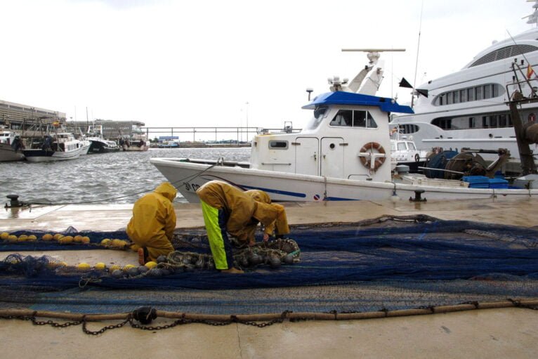 Pescadores trabajando en el puerto de Dénia bajo la lluvia