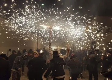 Dimoni und Gruppen von Menschen, die unter den Feuern tanzen