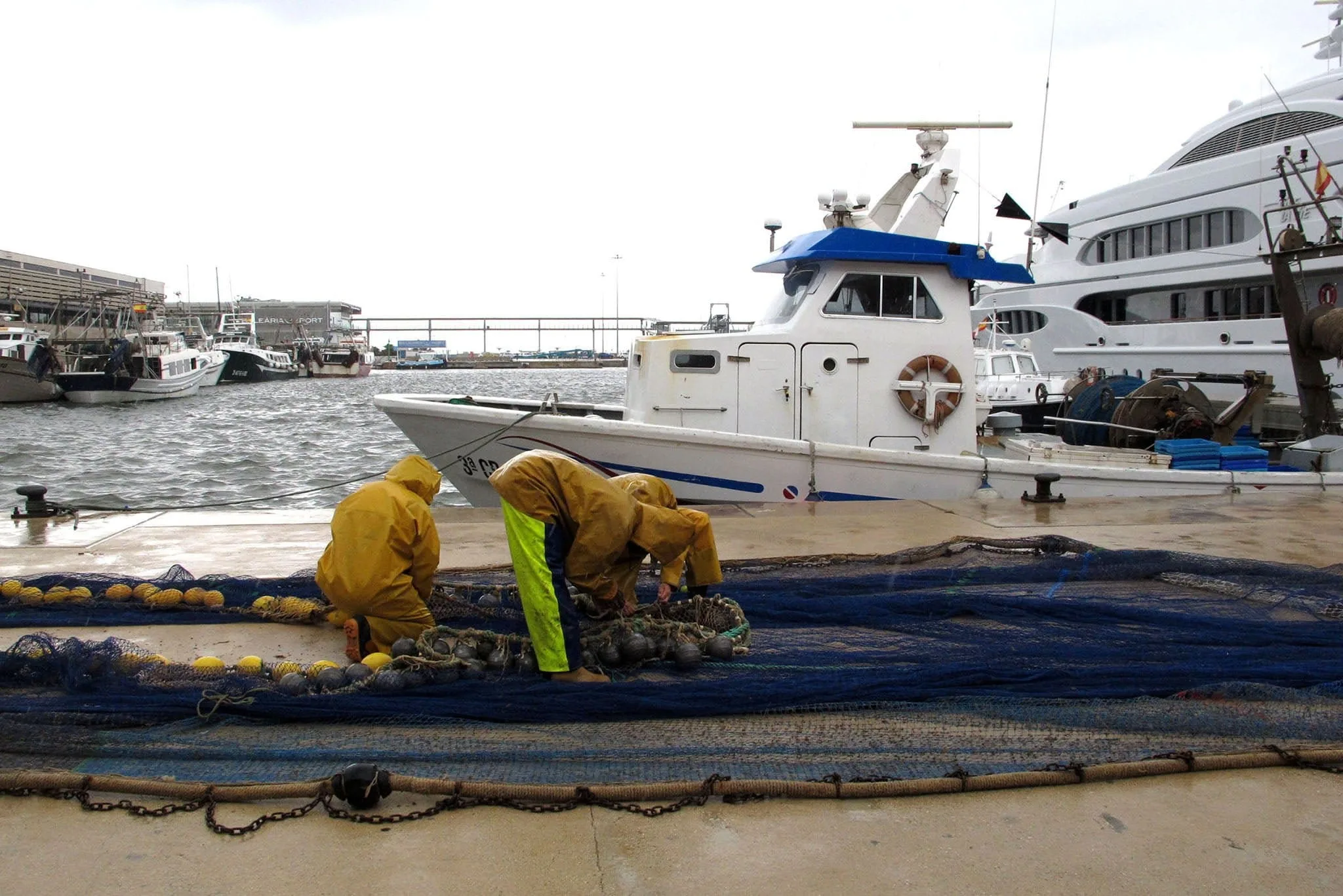 pescadores trabajando en el puerto de denia bajo la lluvia