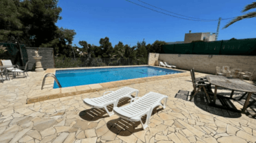 Piscina con conjunto de comedor exterior y hamacas para tomar el sol