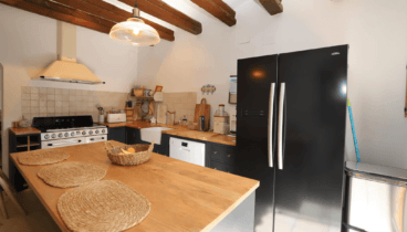 Cocina de estilo industrial con isla central con banco de madera