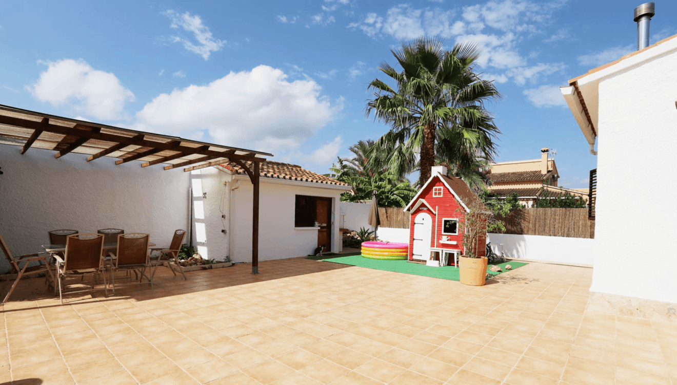 Exterior de la vivienda con pérgola y comedor exterior