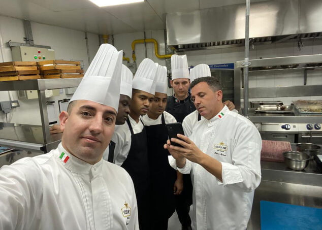 Imagen: Marco Blanquer y Rafa Soler detrás mostrando varios de sus platos al equipo de cocina en Dubái