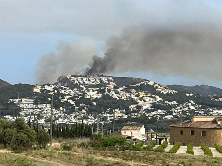 De vlammen en rook zichtbaar op de top van de Barranc de la Viuda de Benitatxell naast de baai van Llebeig
