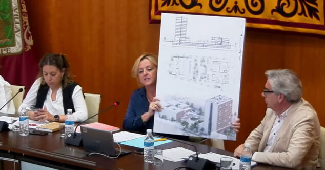 Imagen: Ana Sala mostrando el póster con el proyecto del complejo inmobiliario en el pleno de mayo 2023