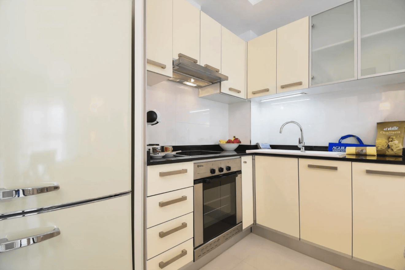 Cocina bien equipada de Town Apartment con horno, cafetra y muebles de tonos claros