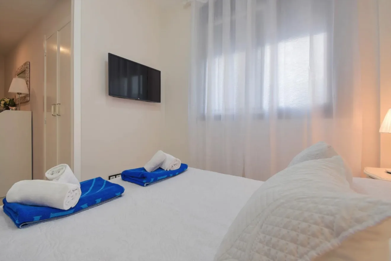 Dormitorio principal de Town Apartment con luz natural y televisión