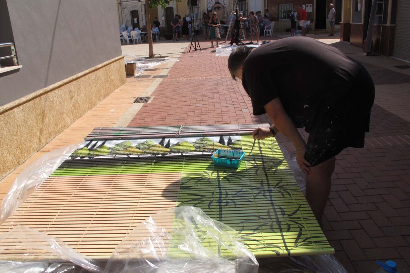 Artista de 'Persianes amb art' en la plaça del Castell de Els Poblets
