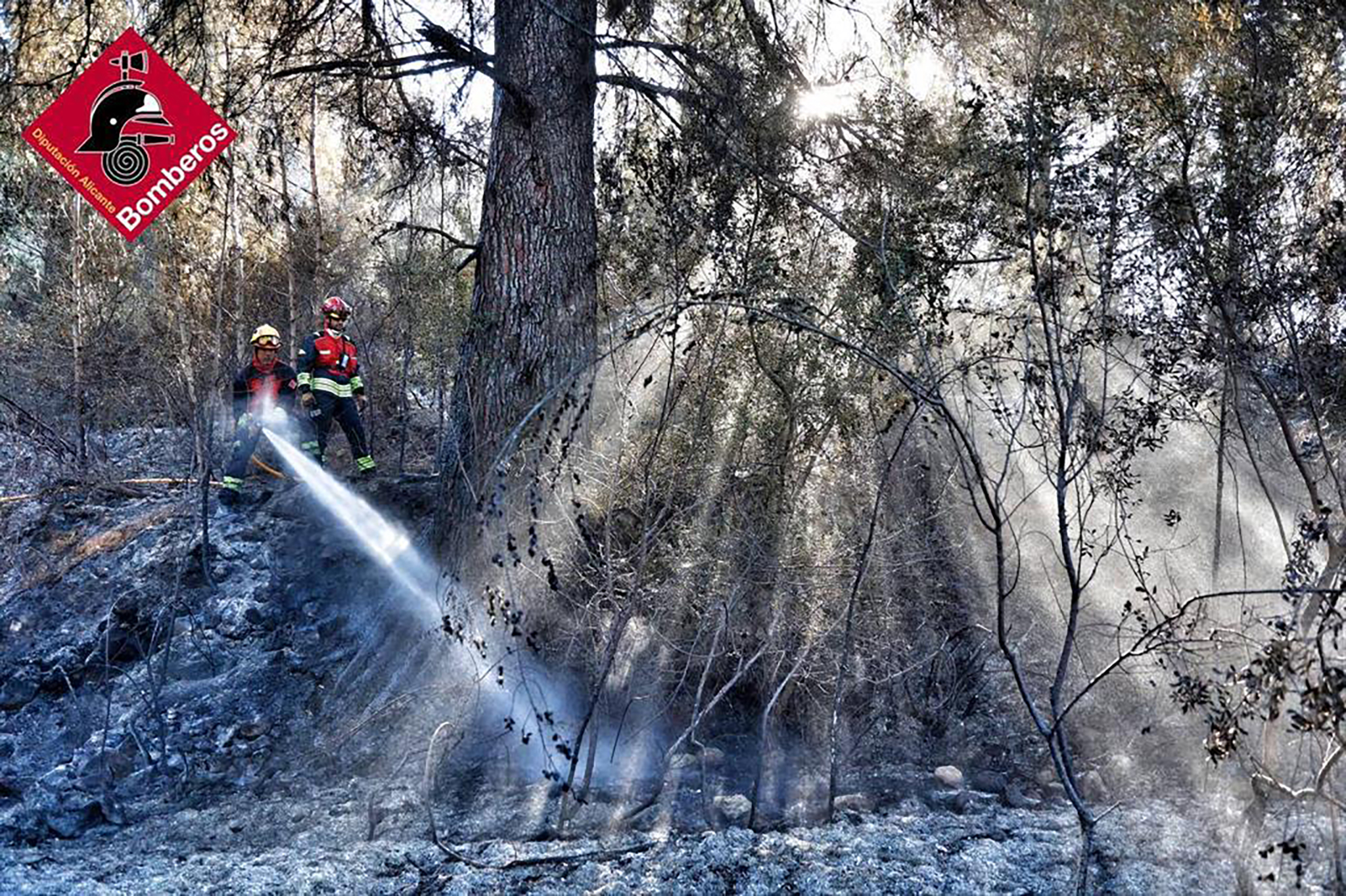 bomberos refrescando la zona del incendio en la serra de segaria