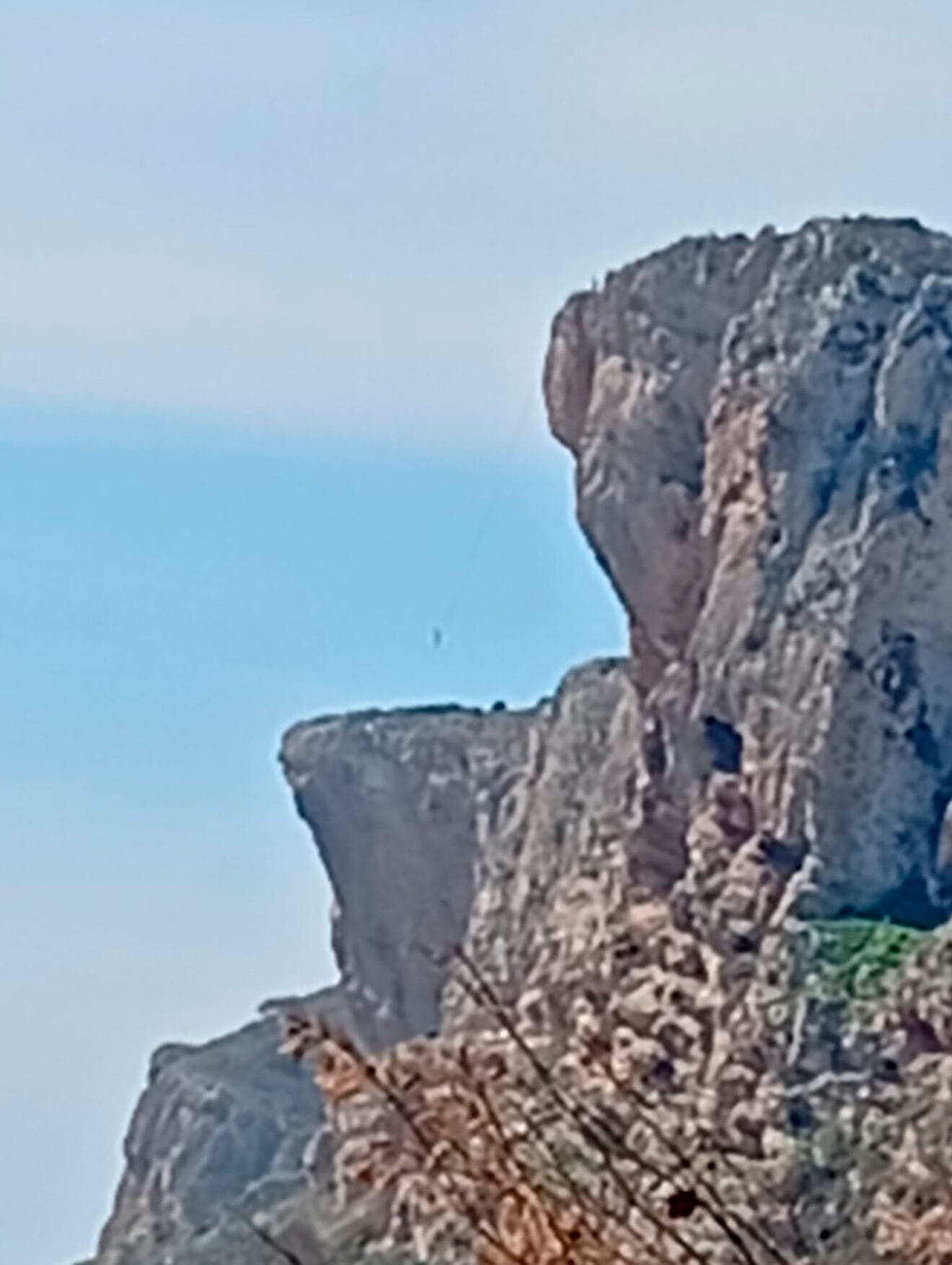 Zoom a la persona funambulista colgada entre los acantilados de Benitatxell