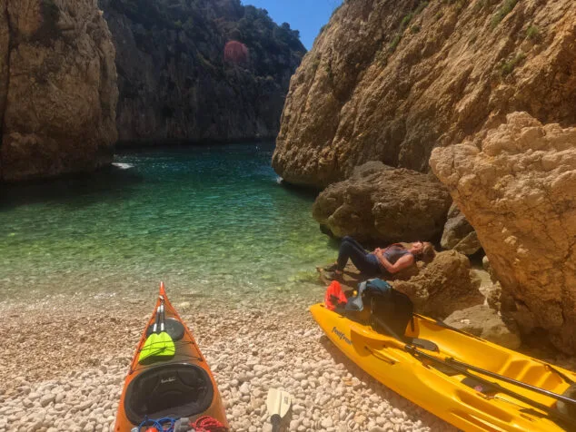 Imagen: Excursionista descansando en un kayak en una cala de Xàbia
