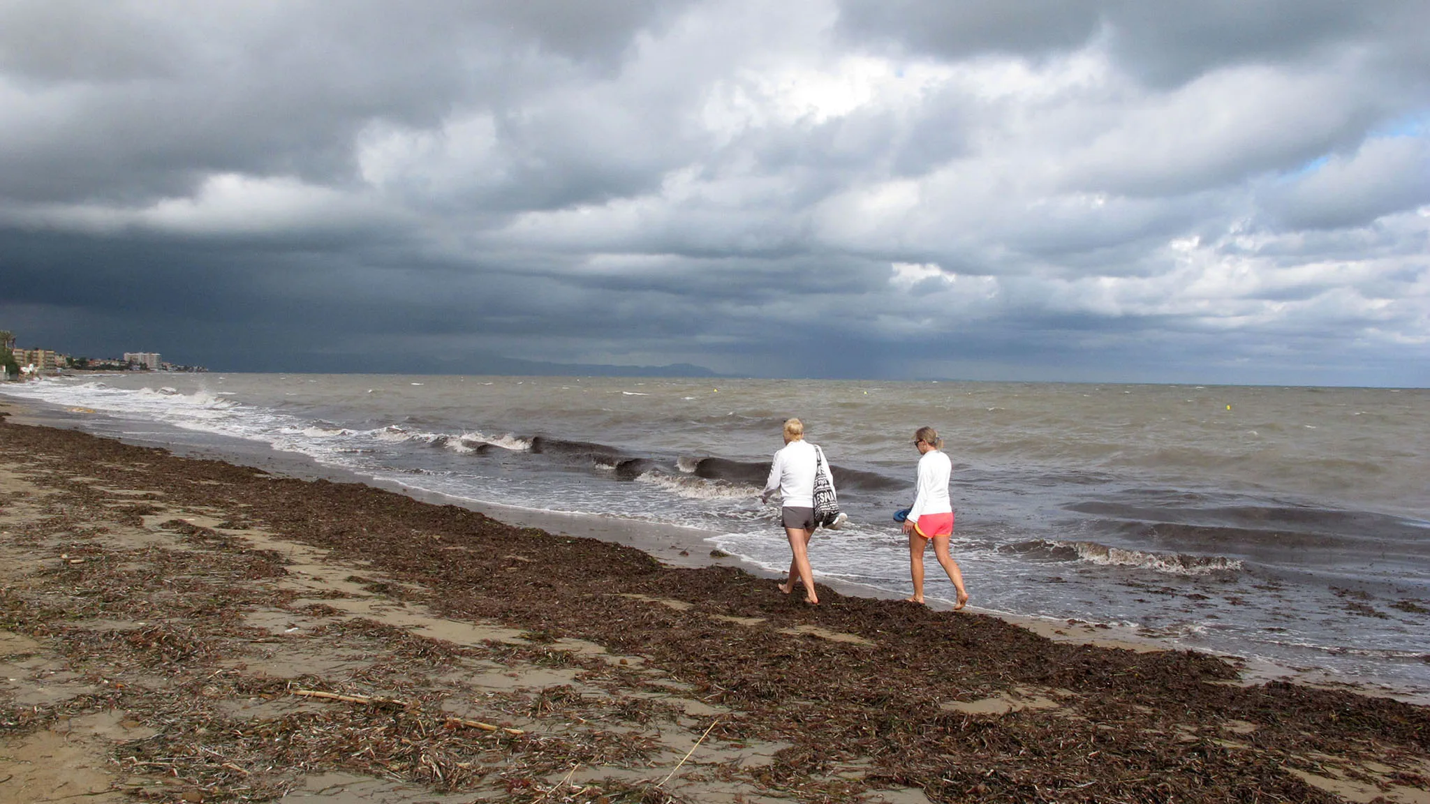 pareja paseando por la orilla tras una tormenta archivo