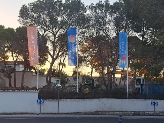 Изображение: Панорамный вид участка, демонстрирующий земляные работы и расчистку кустарника, с растущими соснами в верхней части участка.