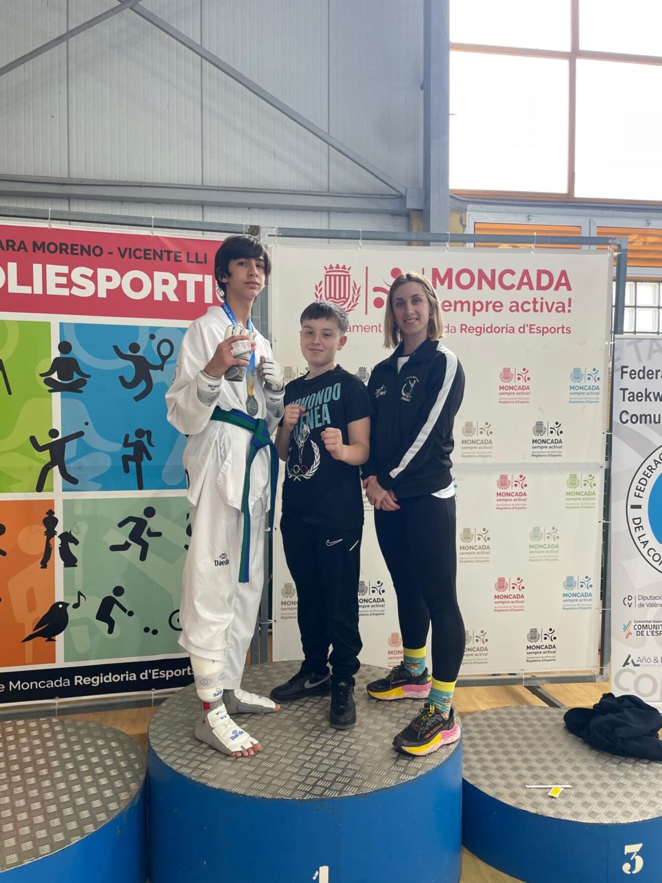 Vertreter des Athenea Taekwondo Clubs aus Calp posieren zusammen mit ihrer Trainerin Nora Ruiz Alcázar auf dem Podium der Regionalmeisterschaft in Moncada.