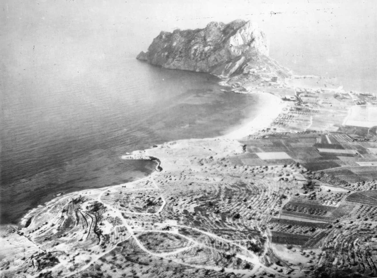 Vista aérea de Calp en las primeras décadas del siglo XX, con el Peñón de Ifac dominando el paisaje, un litoral prácticamente virgen y un territorio marcado por la actividad agrícola