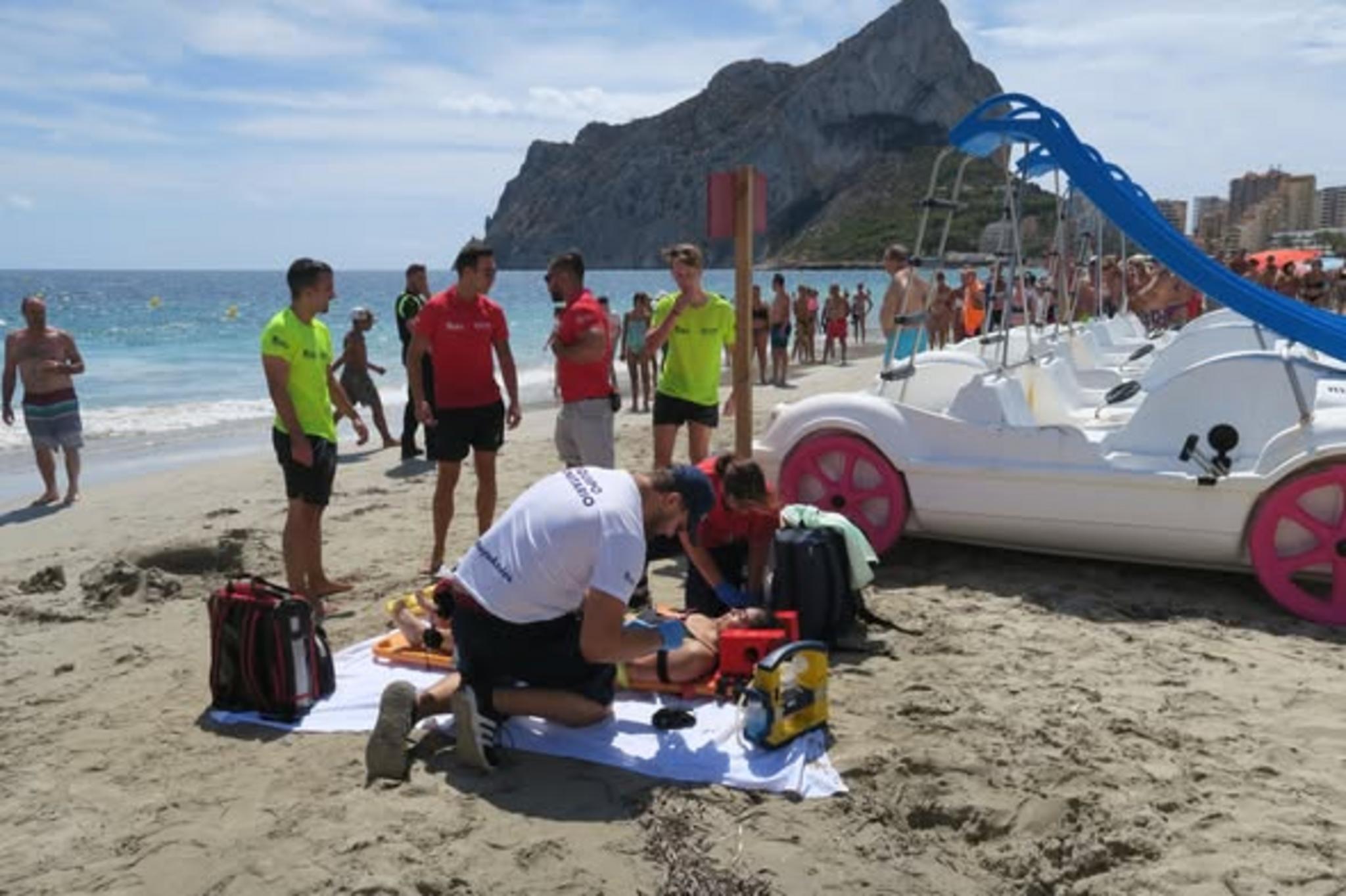 Socorristas atendiendo a una persona en la playa de Calp con el Peñón de Ifach al fondo.