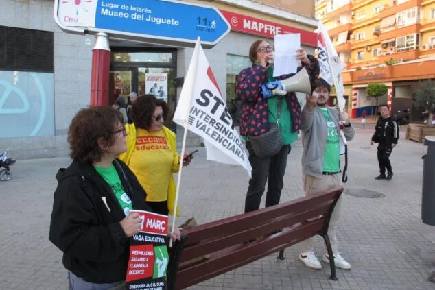 Representantes de sindicatos educativos protestan con megáfono, banderas de STEPV y pancartas de CCOO en una plaza de Dénia.