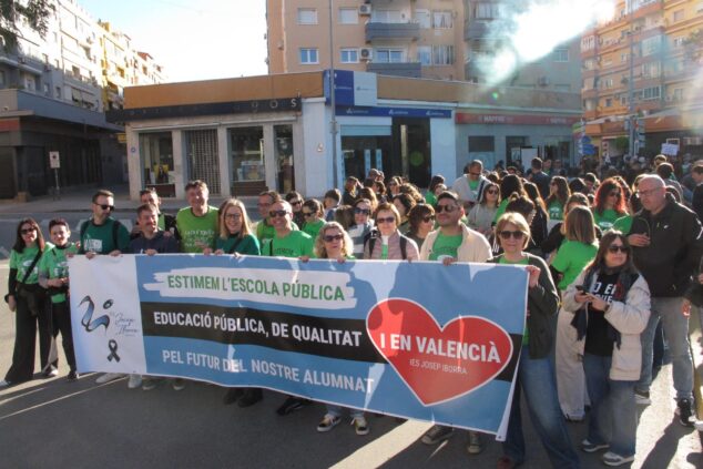 Manifestantes sostienen una gran pancarta a favor de la educación pública y de calidad durante una protesta en una calle de Dénia.