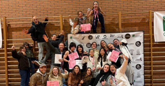 Un grupo animado de personas de la escuela de circo La Marina Social Club posa con diplomas y medallas en un gimnasio tras una competición aérea.