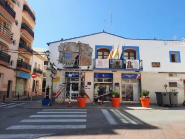 Operario en un andamio evaluando el mosaico de Gastón Castelló en la fachada de la oficina de turismo de Calp.
