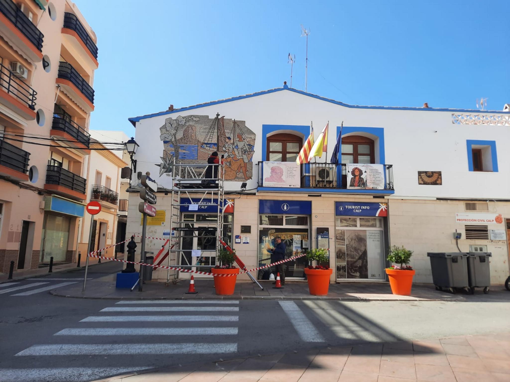 Operario en un andamio evaluando el mosaico de Gastón Castelló en la fachada de la oficina de turismo de Calp.