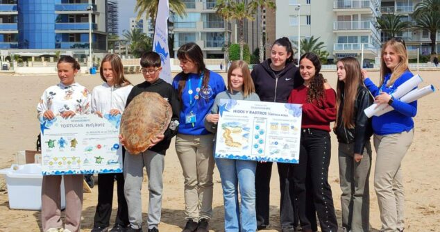 Imagen: Estudiantes y personal de la Fundación Oceanogràfic posan con la tortuga 'Tuk Tuk' y carteles educativos en la playa de Calp antes de su suelta.