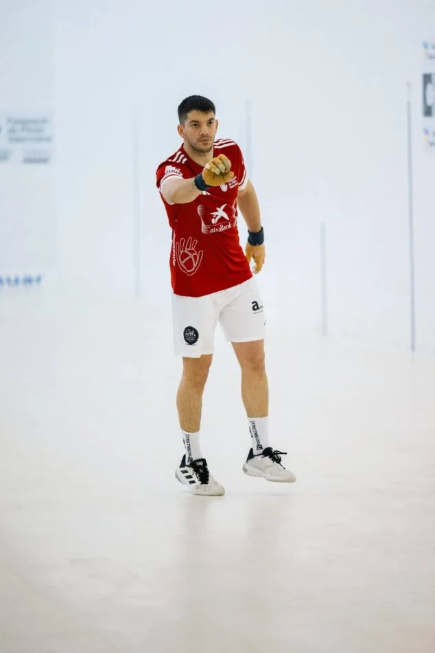 Spieler der valencianischen Pilota-Mannschaft aus Ondara, einer der Terrades-Brüder, im Triquet, der während eines Raspall-Spiels das rote CaixaBank-Trikot trägt.