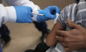 Profesional sanitario administrando una vacuna a un niño.