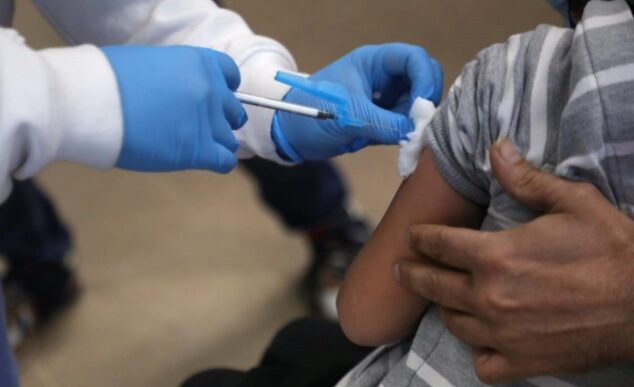 Profesional sanitario administrando una vacuna a un niño.