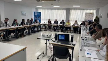 Amplia reunión de trabajo con múltiples asistentes sentados en mesas en forma de U durante la visita institucional de Labora a la sede de Creama en Dénia.