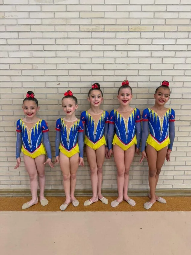 Imagen: Cinco gimnastas del conjunto del CG Les Marines de Calp posando con maillots de competición.