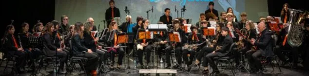 Imatge: Vista general de l´Agrupació Musical CLAUdeFA–CALP actuant en un escenari, amb músics i director.