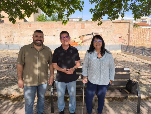 Imagen: Tres personas, representantes del Ayuntamiento de El Verger y un arqueólogo, posan frente a un muro antiguo y maquinaria de obra durante el inicio de los trabajos de recuperación.