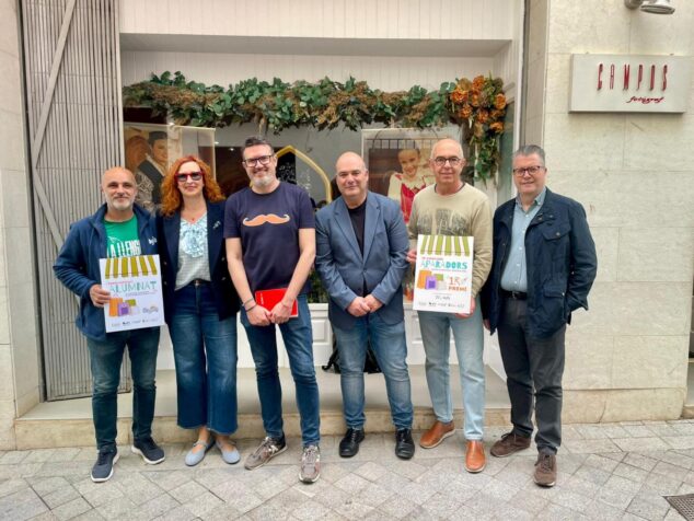 Grupo de personas frente a la tienda Campos Fotògraf sosteniendo carteles de primer premio y premio especial del concurso de escaparates de Benissa.