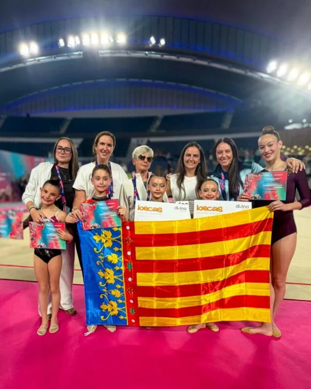 El Club Gimnasia Calpe triunfa en Oviedo con Varvara Kovalenko campeona de España benjamín 3 Imagen: Grupo de gimnastas y entrenadoras del Club Calpe posando con diplomas y una bandera de la Comunidad Valenciana en un pabellón deportivo en Oviedo.