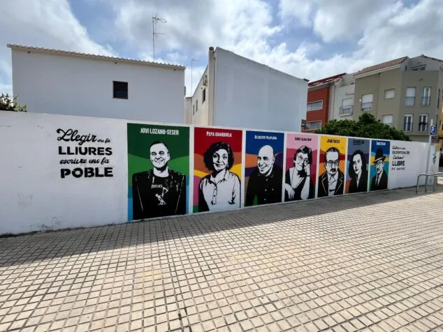 Ondara completa su mural literario con un homenaje al escritor local Jovi Lozano-Seser 1 Imagen: Fotografía del mural literario al aire libre en Ondara, que muestra retratos coloridos de escritores, incluido Jovi Lozano-Seser a la izquierda, y texto en una pared blanca.