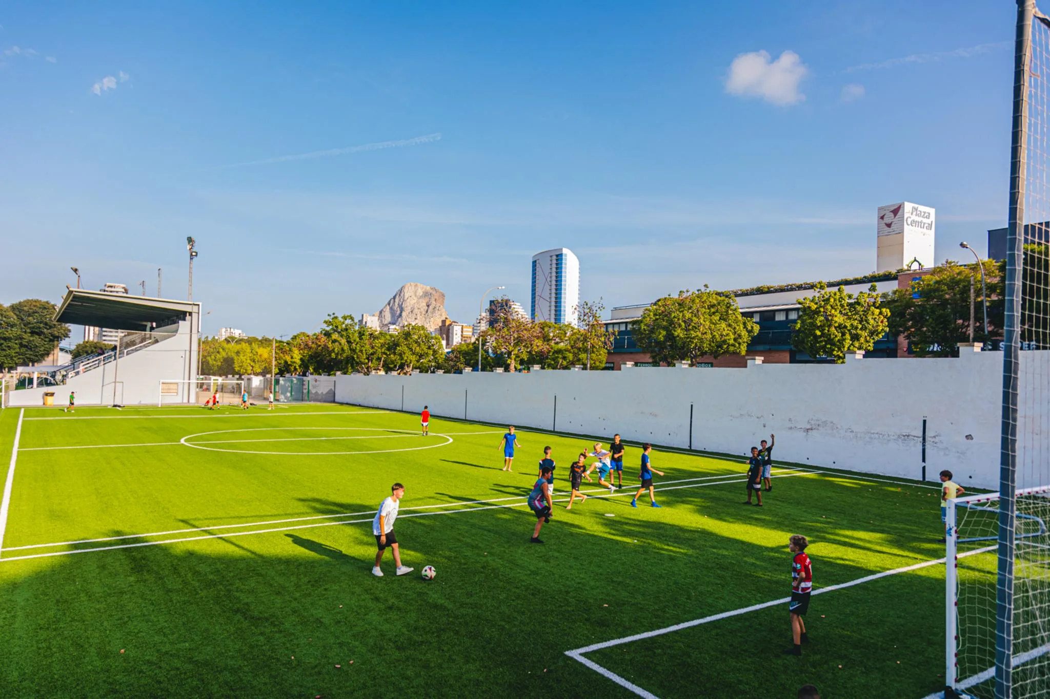Varios niños jugando a fútbol en un campo de césped artificial al aire libre en Calp.