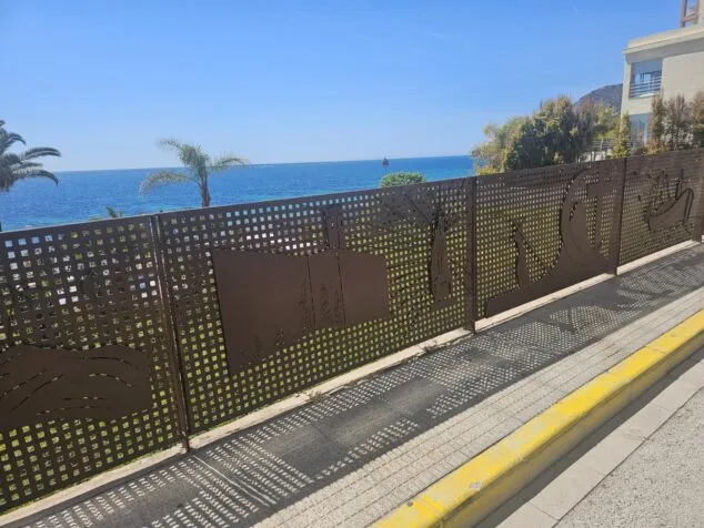 La nueva barandilla artística de Toni Marí, un homenaje a las fiestas y símbolos de Calp 2 Imagen: Barandilla artística de hierro con siluetas de fiestas locales en el paseo marítimo de Calp frente al mar.