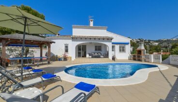 Piscina privada en forma de riñón rodeada de solárium en Benissa