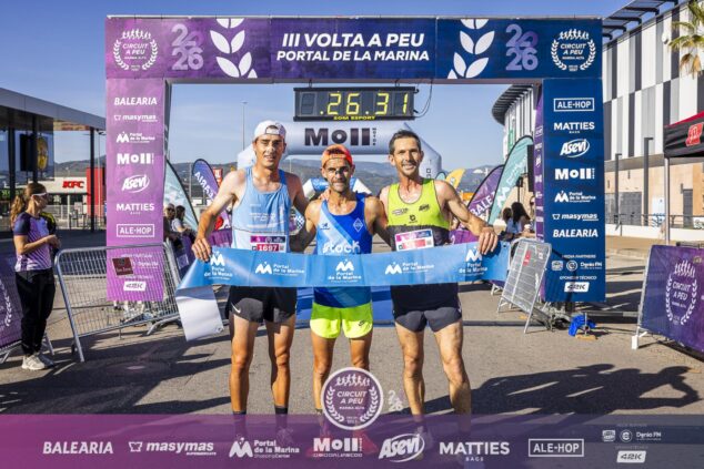 Imagen: Tres corredores en el podio de la carrera Portal de la Marina bajo el arco de meta con el reloj y patrocinadores.