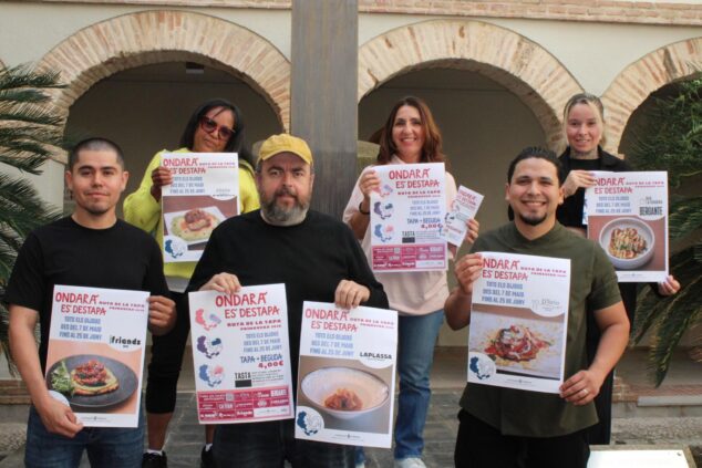 Imagen: Grupo de seis restauradores sosteniendo carteles promocionales de la Ruta de la Tapa de Ondara Primavera 2026 en un patio.