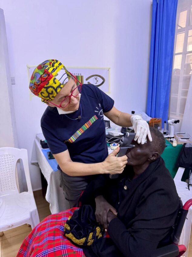 Imagen: Una voluntaria de Visió sense Fronteres usa un instrumento médico para examinar el ojo de una paciente sentada en una silla de ruedas en Kenia.