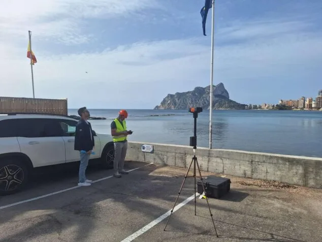 La recuperación del sendero Calalga-Bassetes en Calp, más cerca 1 Imagen: Dos técnicos con equipo de topografía trabajan junto al mar en Calp, con el Peñón de Ifach al fondo.