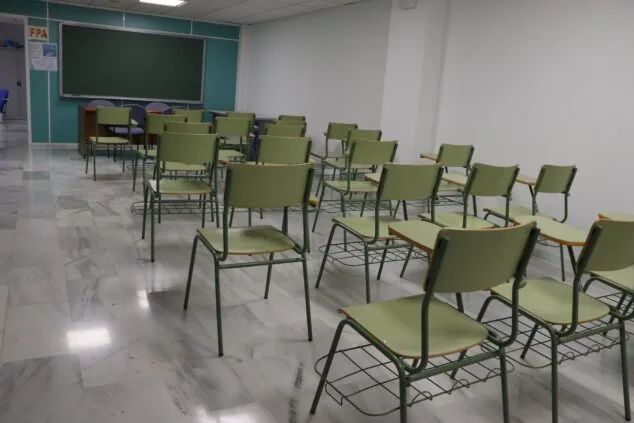 Imagen: Vista interior de un aula de Formación Profesional con pupitres verdes vacíos y una pizarra.