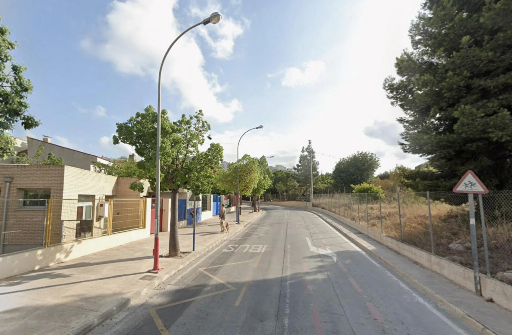 Vista de la calle Miguel Hernández de Calp, con una farola antigua y señalización escolar.