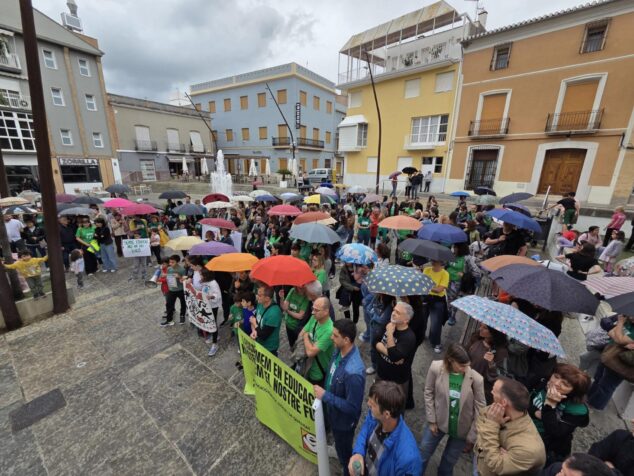 Imagen: Multitud concentrada bajo la lluvia en la plaza del Ayuntamiento de Pego con pancartas en defensa de la educación pública.