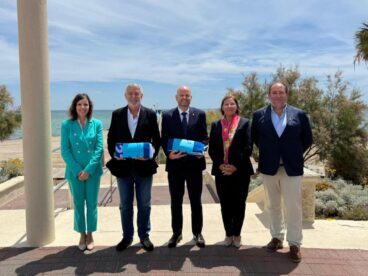 Representantes del Club Náutico Moraira y del Ayuntamiento de Teulada Moraira posan con las Banderas Azules en un acto al aire libre.