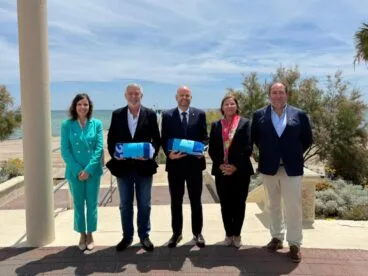 Representantes del Club Náutico Moraira y del Ayuntamiento de Teulada Moraira posan con las Banderas Azules en un acto al aire libre.