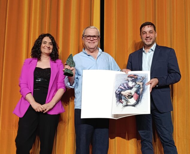 Imagen: Josep Puig Ramis recibe el Premio Ocell 2025 de manos de Rosa Ana Marí y José Ramiro en el escenario.