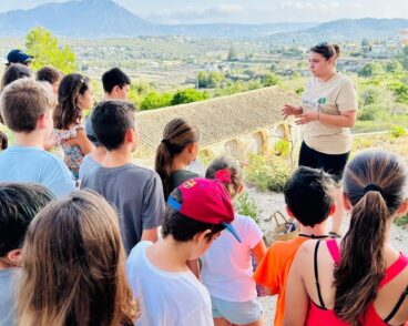 Grupo de niños y monitora en una excursión al aire libre mirando un paisaje.